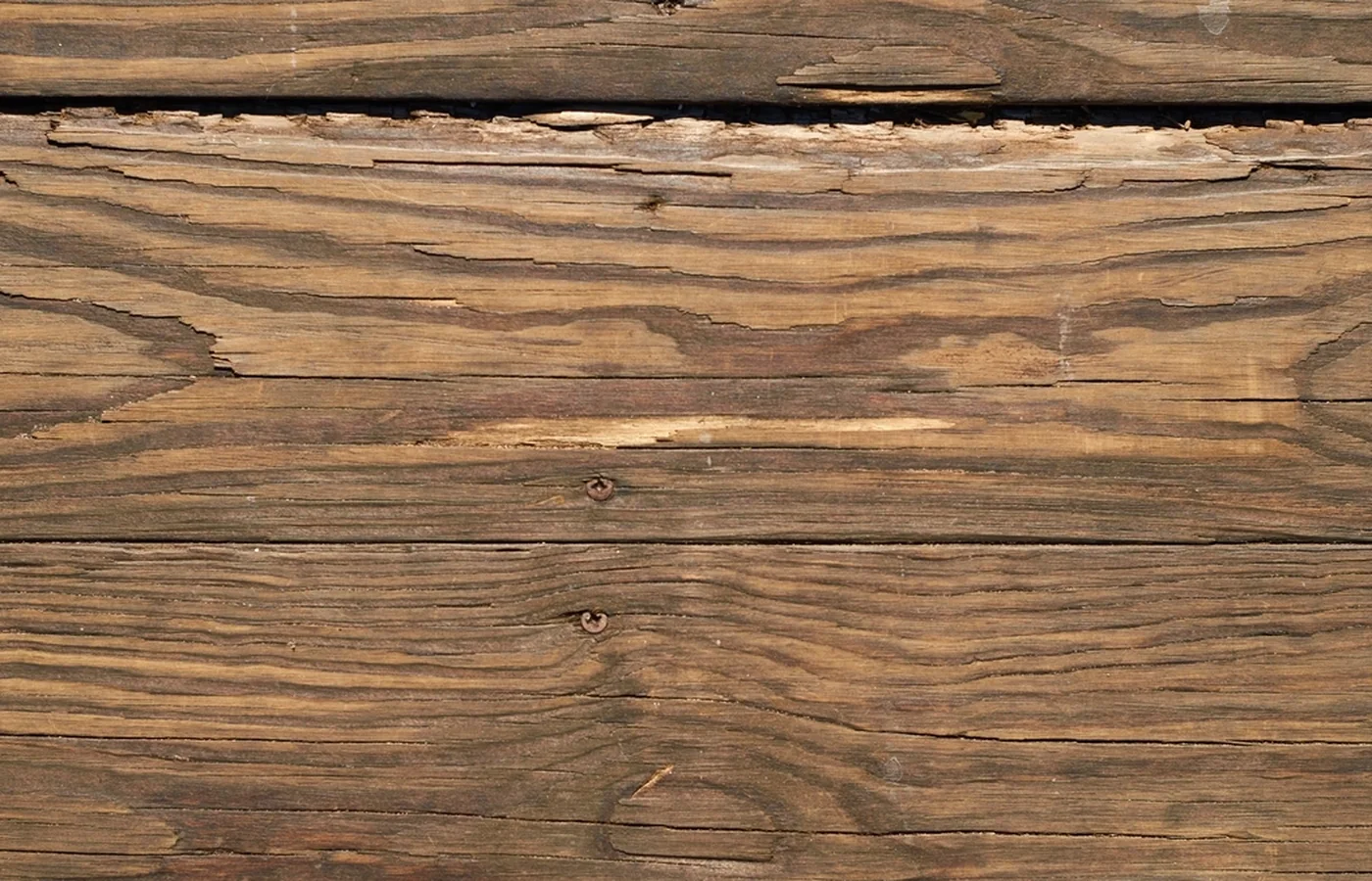 Close-up of a split, checked deck board beside a wide gap