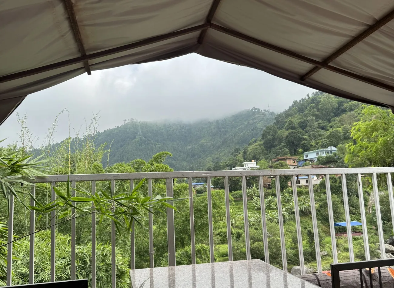 Roofed deck with a metal railing looking out over a wooded valley