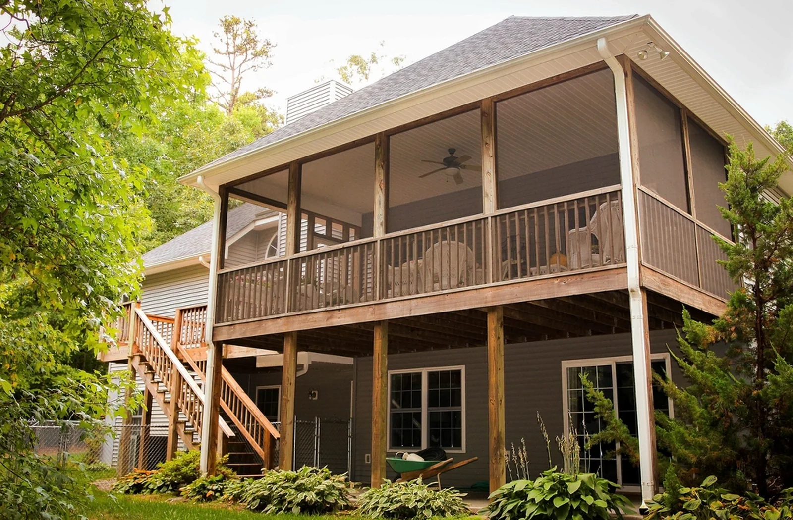 Two-story home with a screened upper porch over an elevated wood deck and stairs